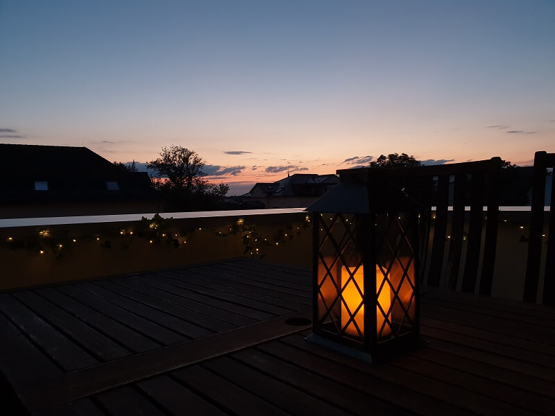 Sonnenuntergang auf dem Balkon mit stimmungsvoller Kerzen-Laterne und Lichterkette