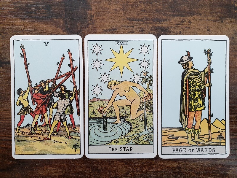 Reflexion mit Tarot im Juli 2024: 3 zufällig gezogene Tarotkarten auf einem Holztisch